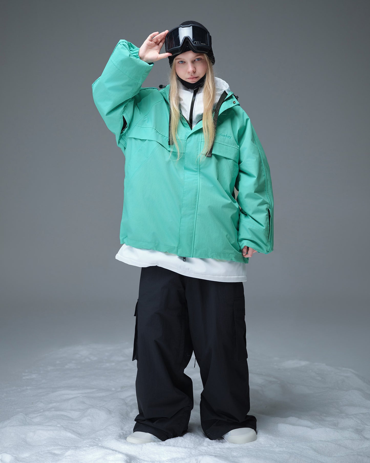 Full body layered look of Nobaday Women's Pure Free Active blue snow jacket with black snow pants, goggles, and relaxed snowboard fit