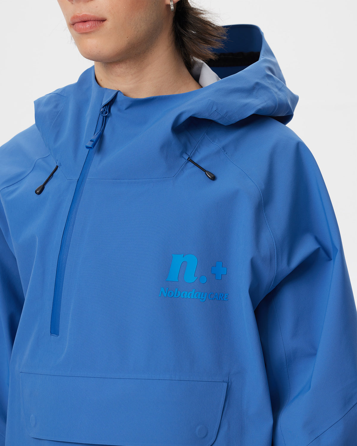 Close-up of the high collar, half-zip closure, adjustable hood and Nobaday Care logo on the blue ArcticStorm 3L Anorak Snow Jacket