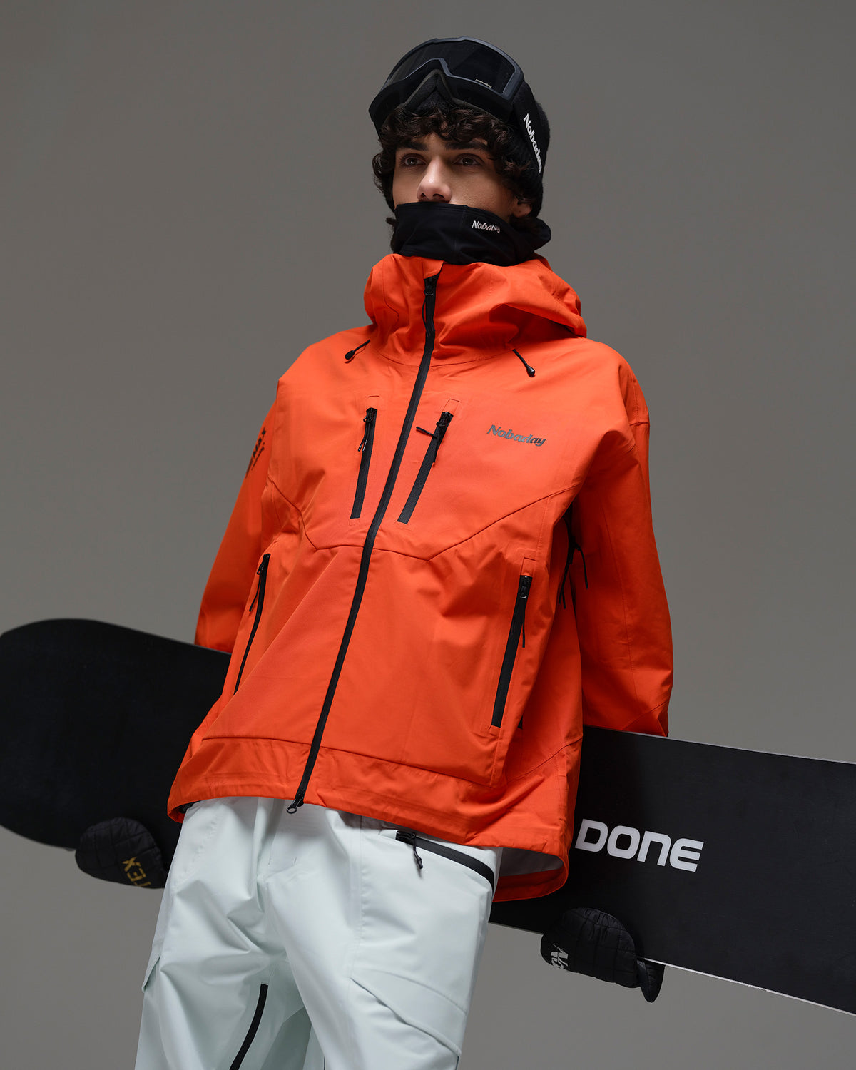 Male snowboarder wearing the NOBADAY Men’s MaxExtreme Pro 3L snow jacket in orange while holding a snowboard