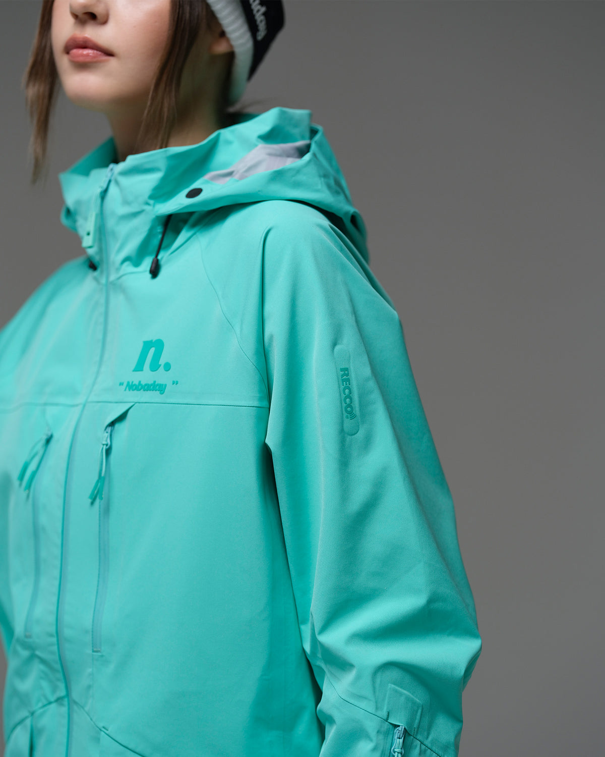 Close-up of the NOBADAY Women's ArcticStorm Freeride 3L blue snow jacket showing the hood, logo, and waterproof chest zippers