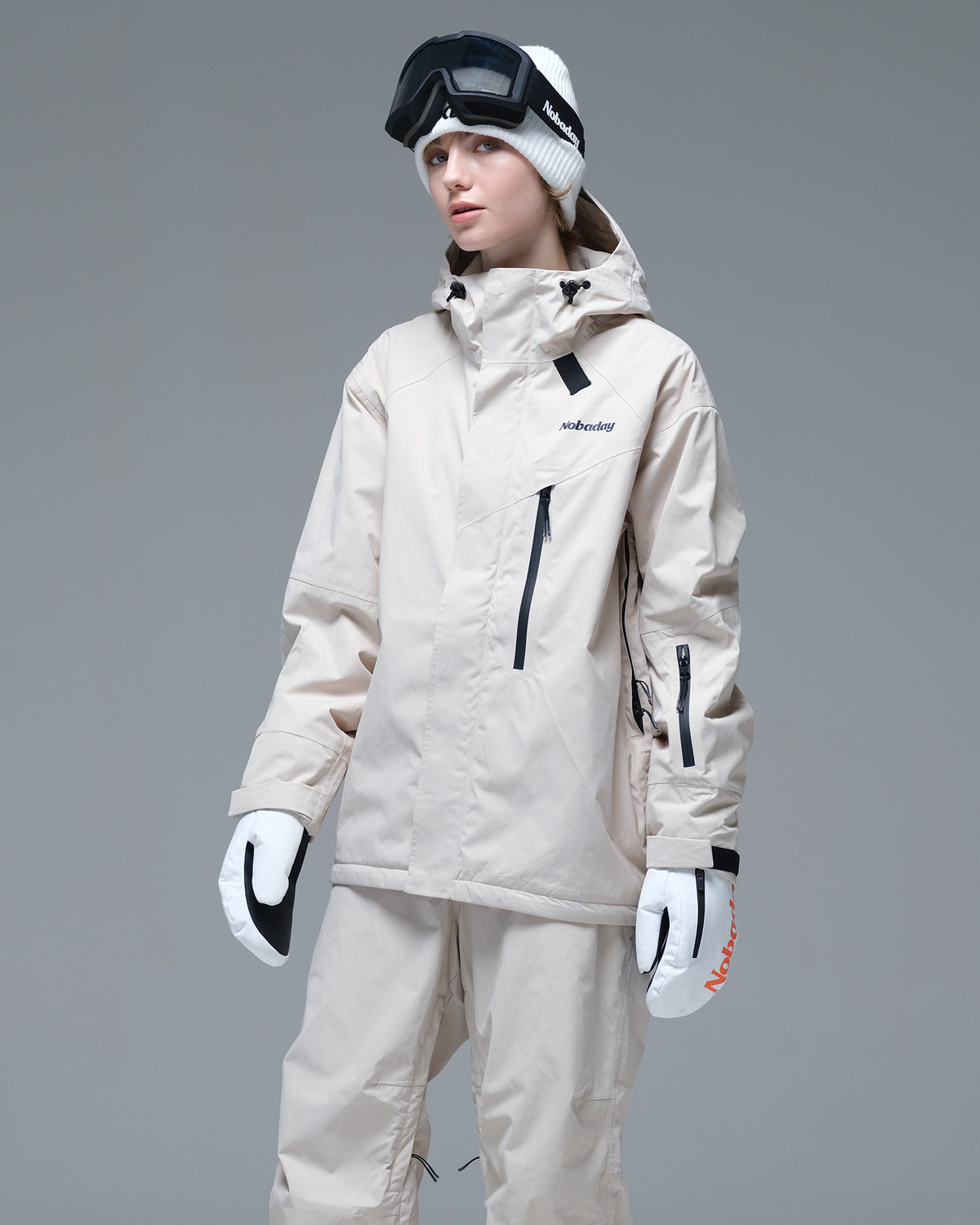 Half-body pose of a woman wearing the NOBADAY Women's Baggy Insulated beige snow jacket with an adjustable hood and waterproof chest pocket