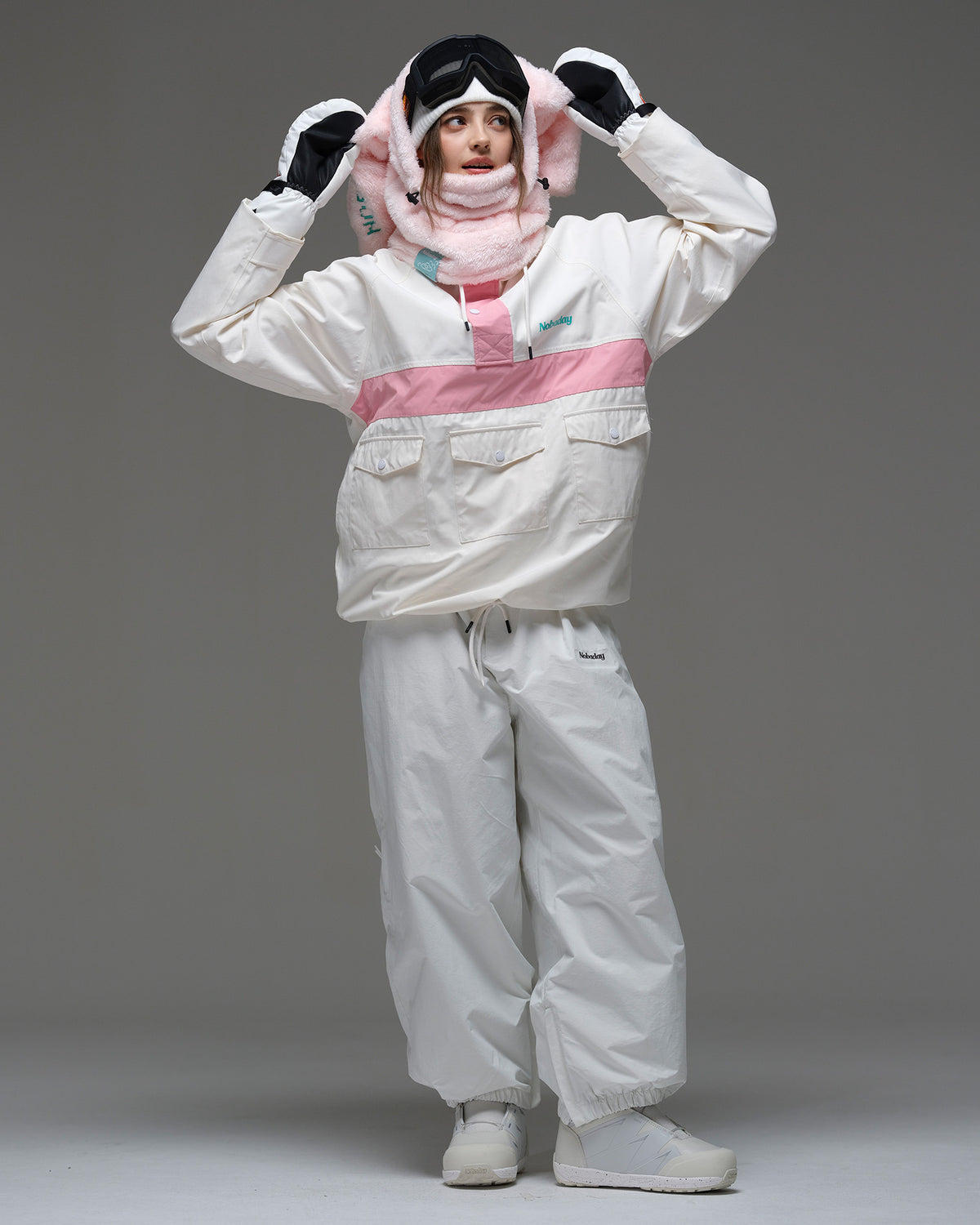 Full-body view of a model wearing the ivory and pink Nobaday Women’s Juicy Candy Retro Snow Jacket with white snow pants