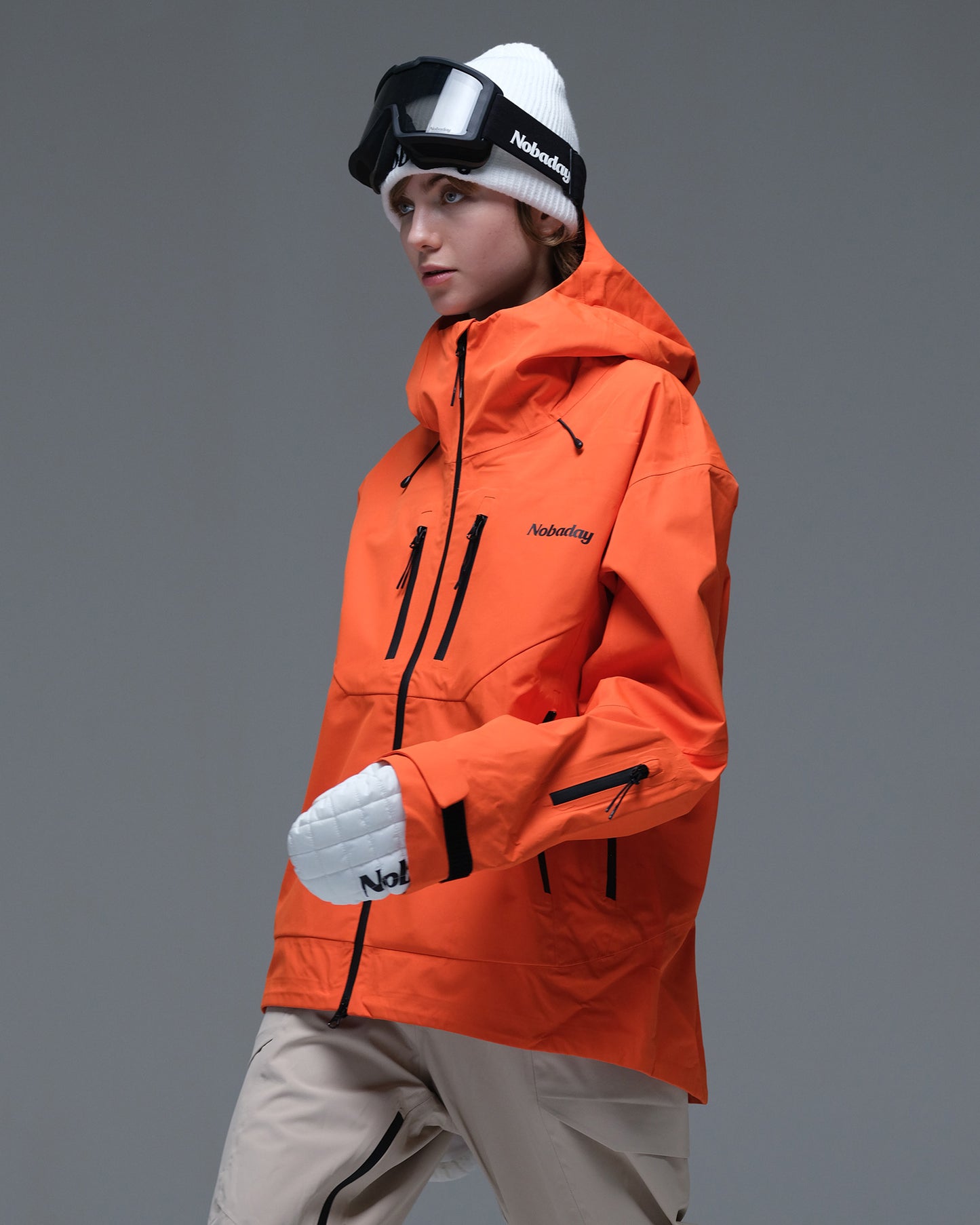 Side view of the orange Nobaday Women’s MaxExtreme Pro Zip-Up 3L Snow Jacket with a high collar and sleeve pocket