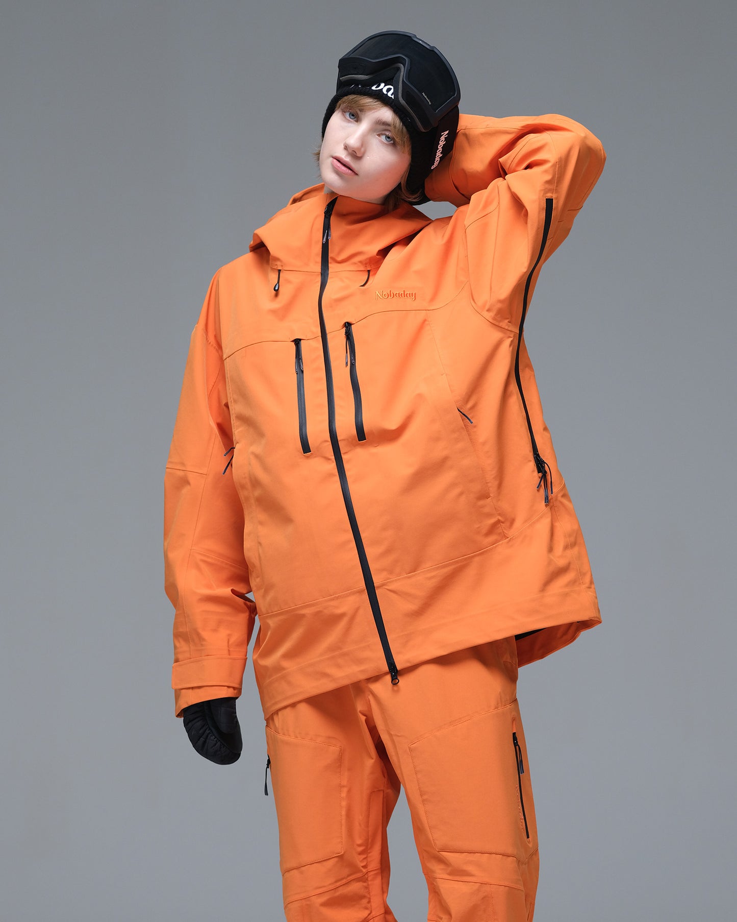 Half-body pose of a woman wearing the NOBADAY Women's Pure Free 3L orange snow jacket with an adjustable hood and chest pockets
