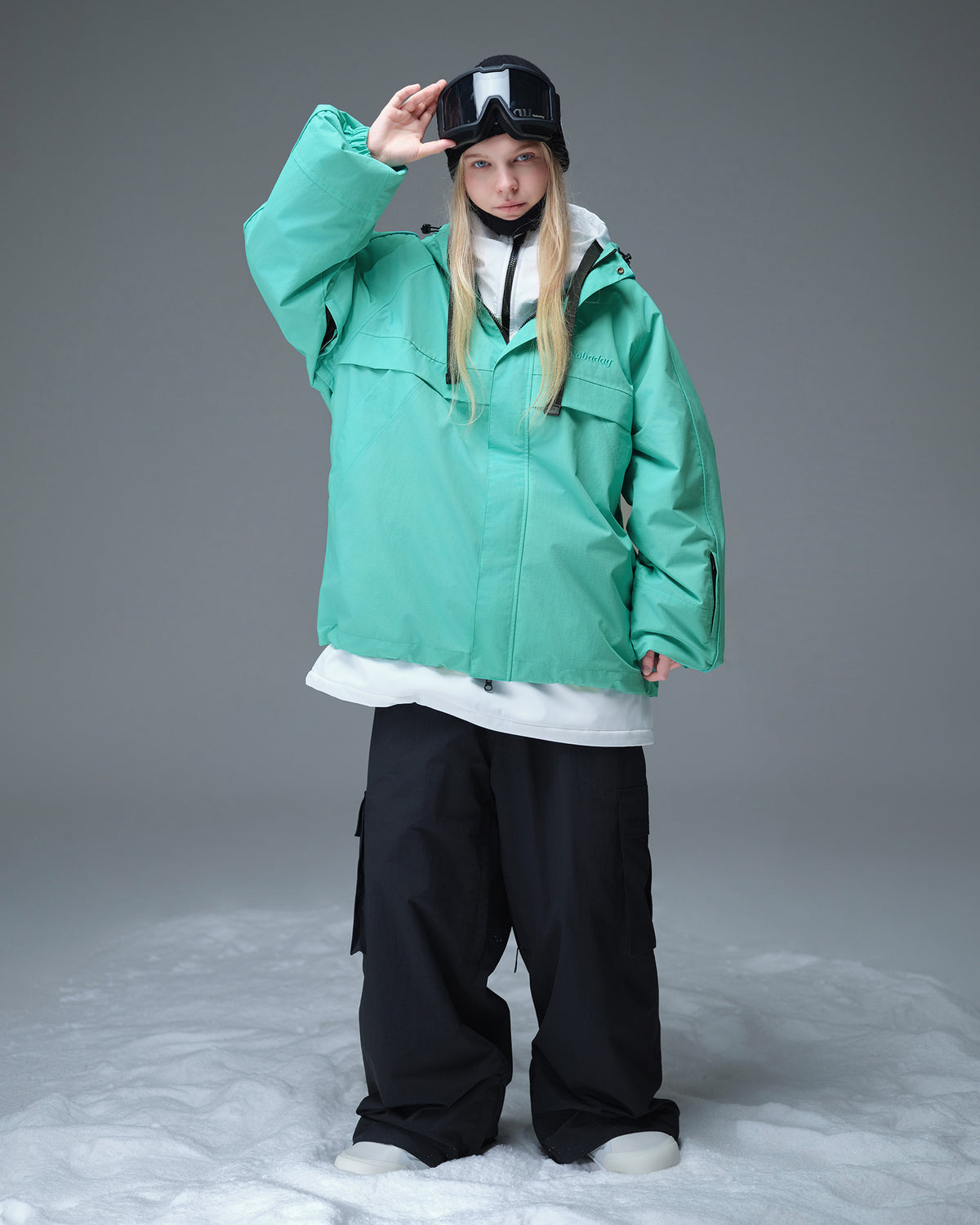 Full body layered look of Nobaday Women's Pure Free Active blue snow jacket with black snow pants, goggles, and relaxed snowboard fit