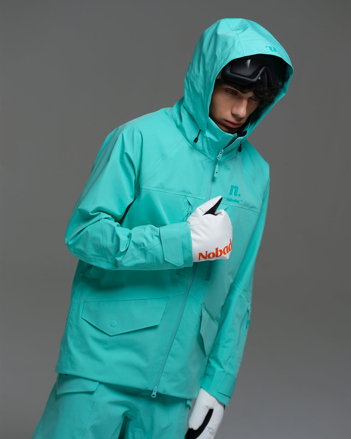 Male snowboarder wearing the NOBADAY Men’s ArcticStorm Freeride 3L snow jacket in Nobaday Blue with the hood up