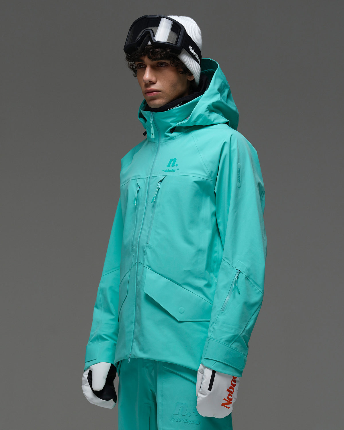 Side view of the NOBADAY Men’s ArcticStorm Freeride 3L blue snow jacket showing the hood, chest zippers, and large flap pockets