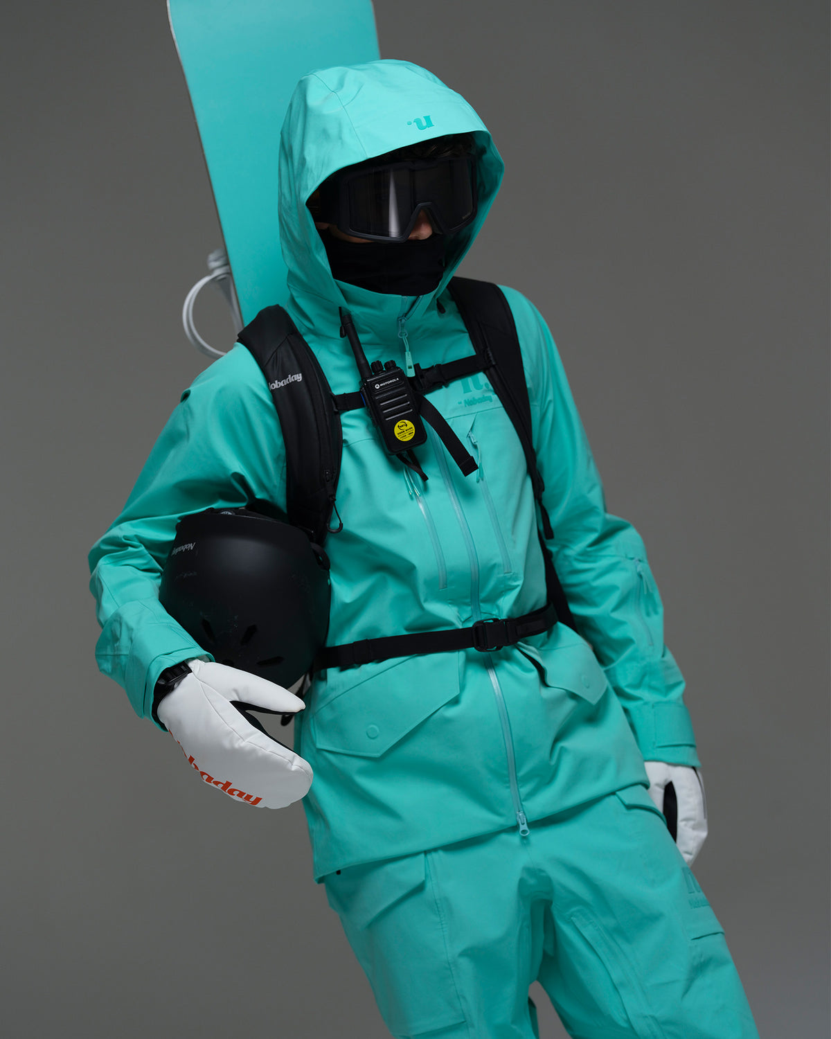 Male snowboarder wearing the NOBADAY Men’s ArcticStorm Freeride 3L blue snow jacket with goggles, backpack, helmet, and snowboard gear