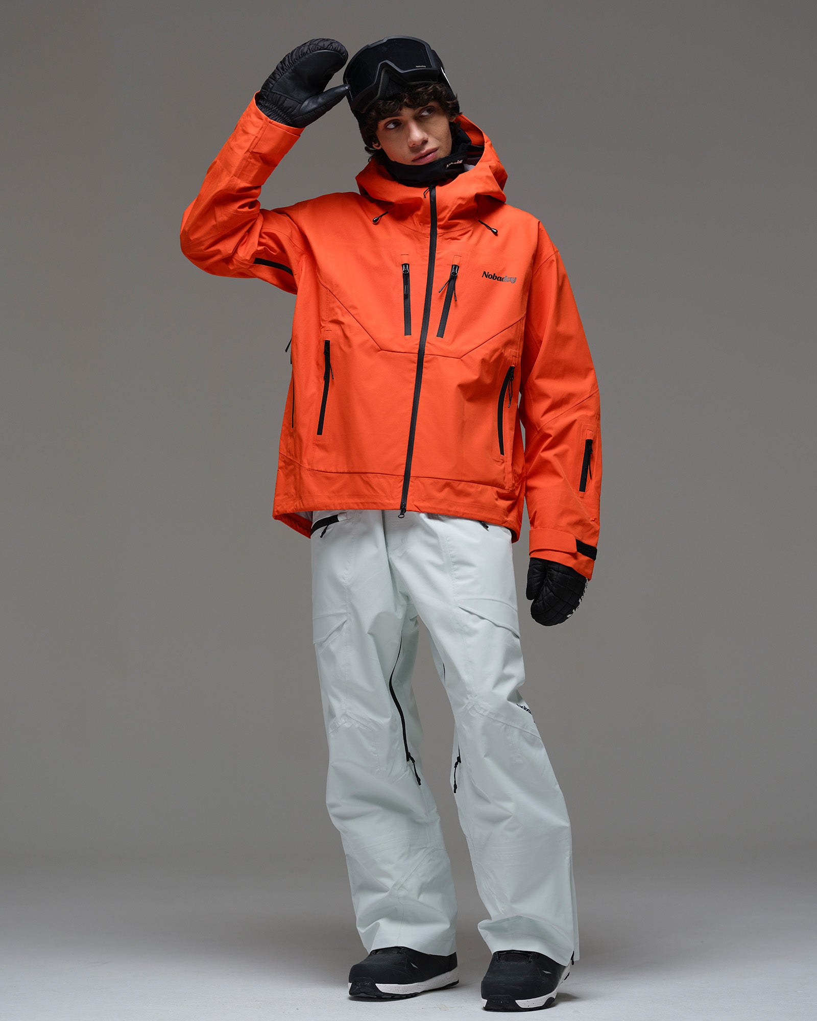 Full-body front view of a man wearing the NOBADAY Men’s MaxExtreme Pro 3L snow jacket in orange with white snow pants