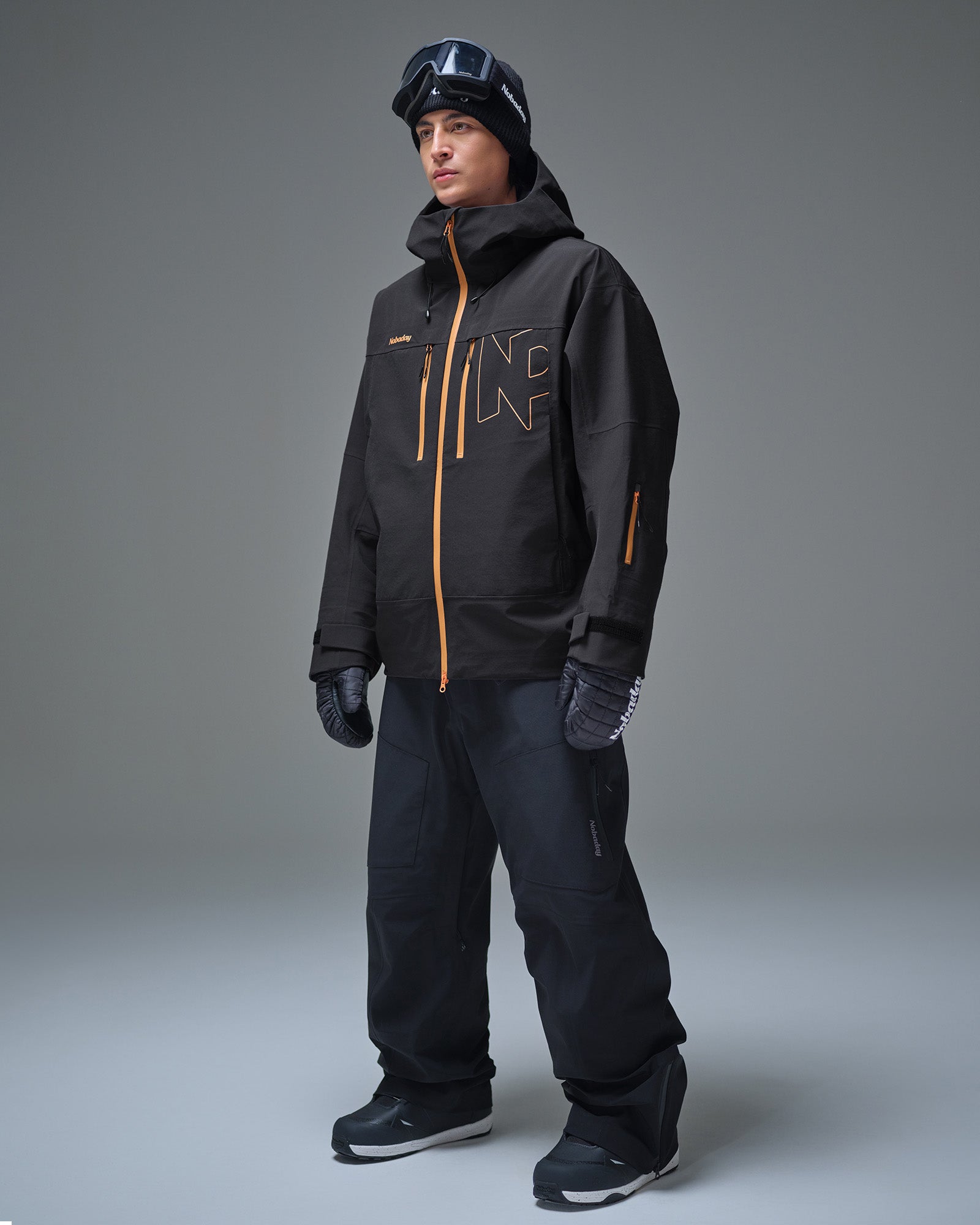 Full-body view of a man wearing the black NOBADAY Apex 3L snow jacket and black snow pants