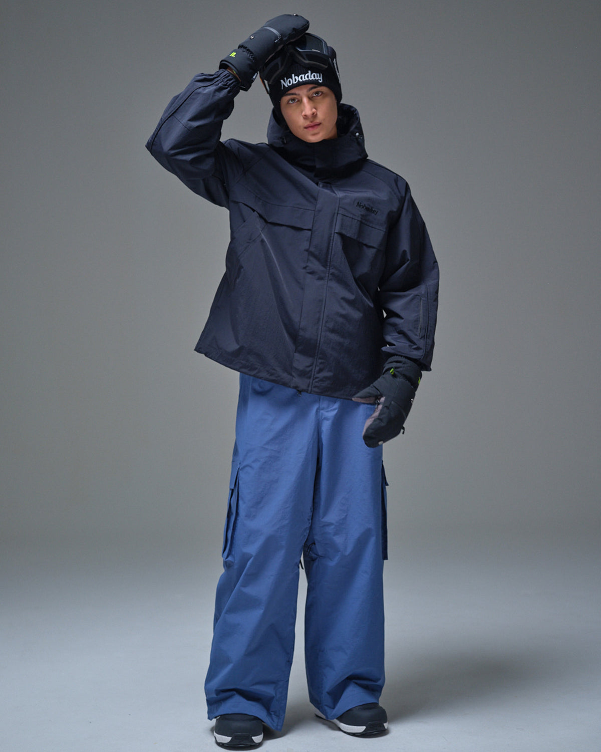 Man wearing a black NOBADAY Pure Free snow jacket with blue snowboard pants