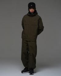 Full-body view of a man wearing a dark green NOBADAY Pure Free snow jacket and matching snow pants