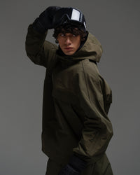 Side view of a man wearing a dark green NOBADAY Pure Free snow jacket with an adjustable hood