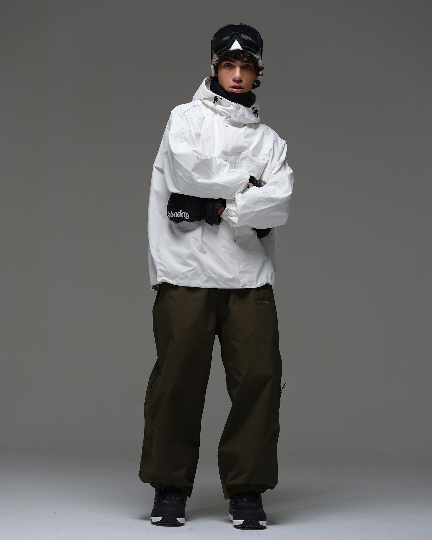 Full-body front view of a man wearing a white NOBADAY Pure Free snow jacket and dark snow pants