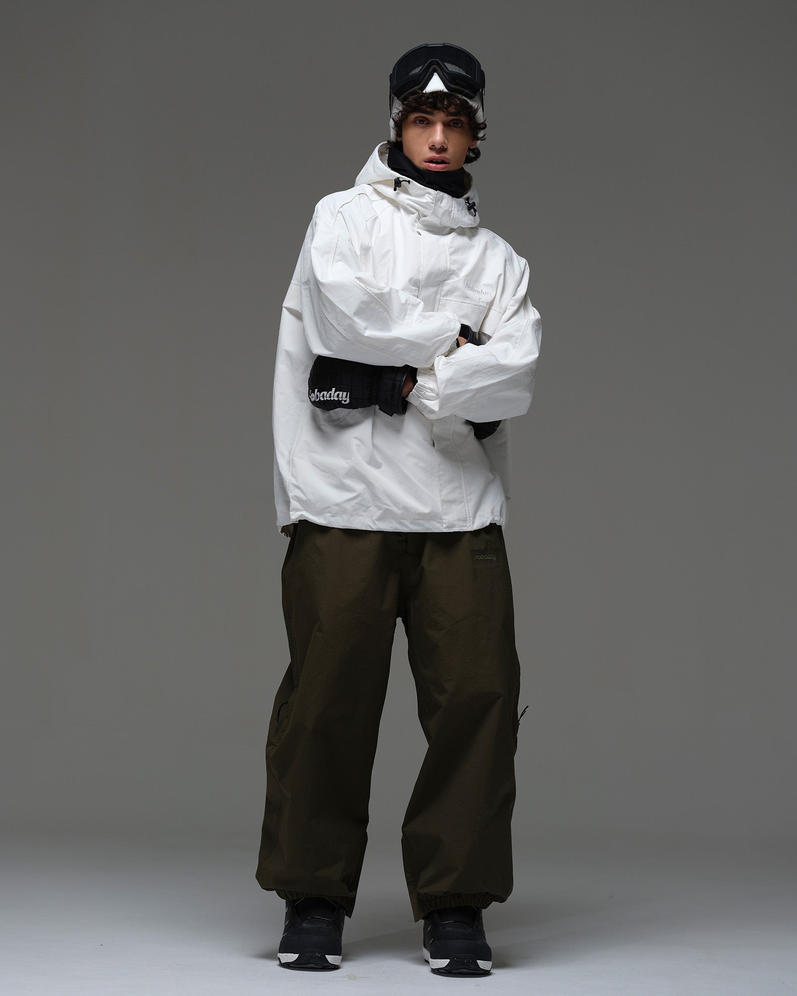 Full-body front view of a man wearing a white NOBADAY Pure Free snow jacket and dark snow pants