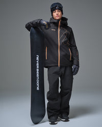 Full-body view of a man wearing the Black NOBADAY Men’s Summit GORE-TEX snow jacket while holding a snowboard