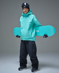 Full-body view of a man wearing the NOBADAY Men’s Summit GORE-TEX snow jacket in Nobaday Blue while holding a snowboard