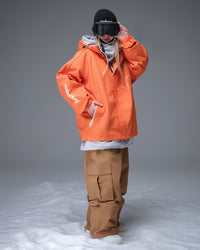 Full body layered look of Nobaday Women's Pure Free Active orange snow jacket with tan snow pants, goggles, and relaxed snowboard fit