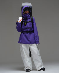 Full body view of Nobaday Women's Pure Free purple waterproof fleece hoodie with white snow pants and snowboard gear