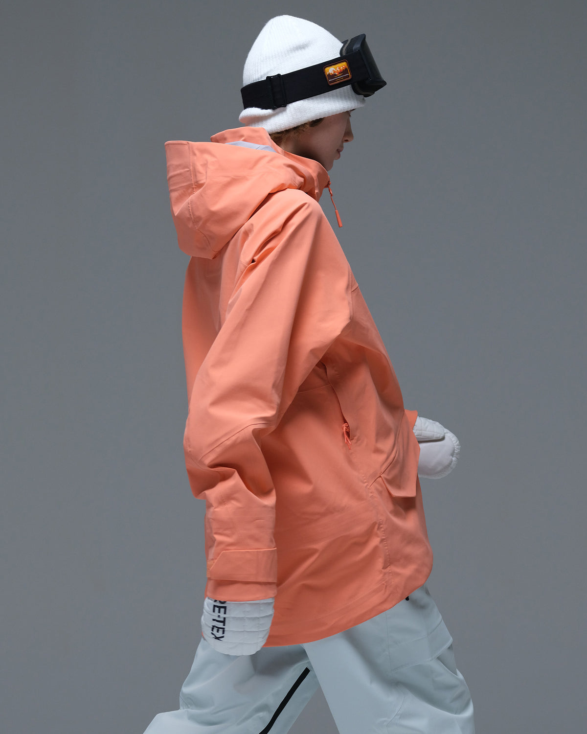 Side view of the coral orange Nobaday Women’s ArcticStorm Freeride Zip-Up 3L Snow Jacket showing its hood and relaxed silhouette