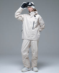 Full-body view of a woman wearing the NOBADAY Women's Baggy Insulated beige snow jacket with matching snow pants