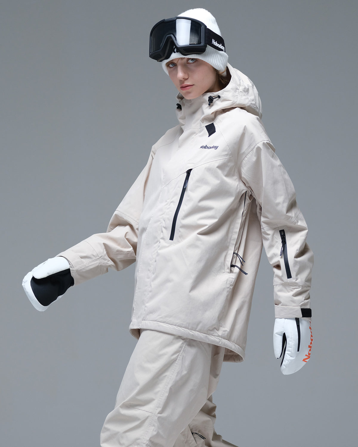 Side view of the NOBADAY Women's Baggy Insulated beige snow jacket showing the chest pocket, lift pass pocket, and adjustable cuff