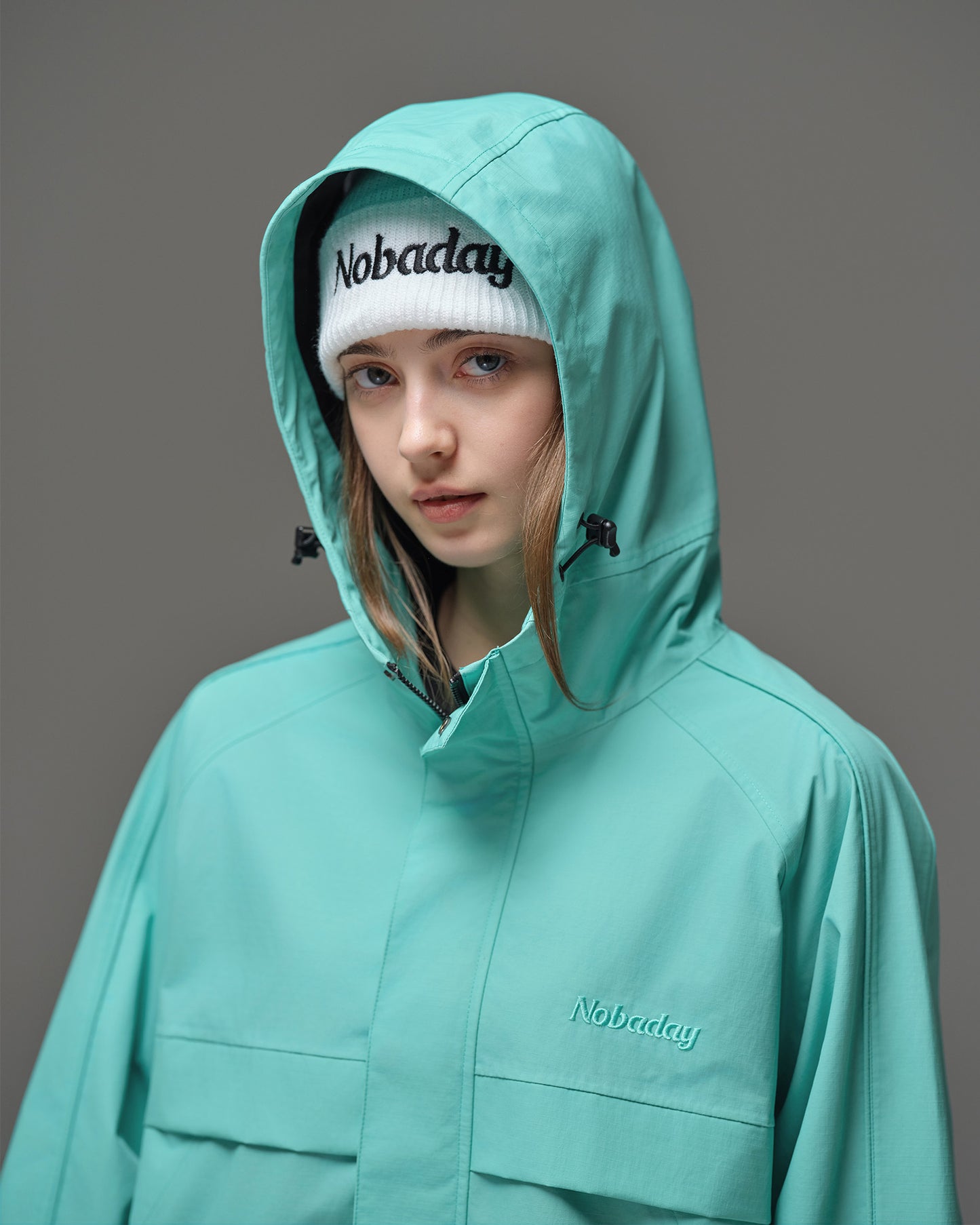Detail of Nobaday Women's Pure Free Active blue snow jacket with adjustable hood, high collar, storm flap, and embroidered logo
