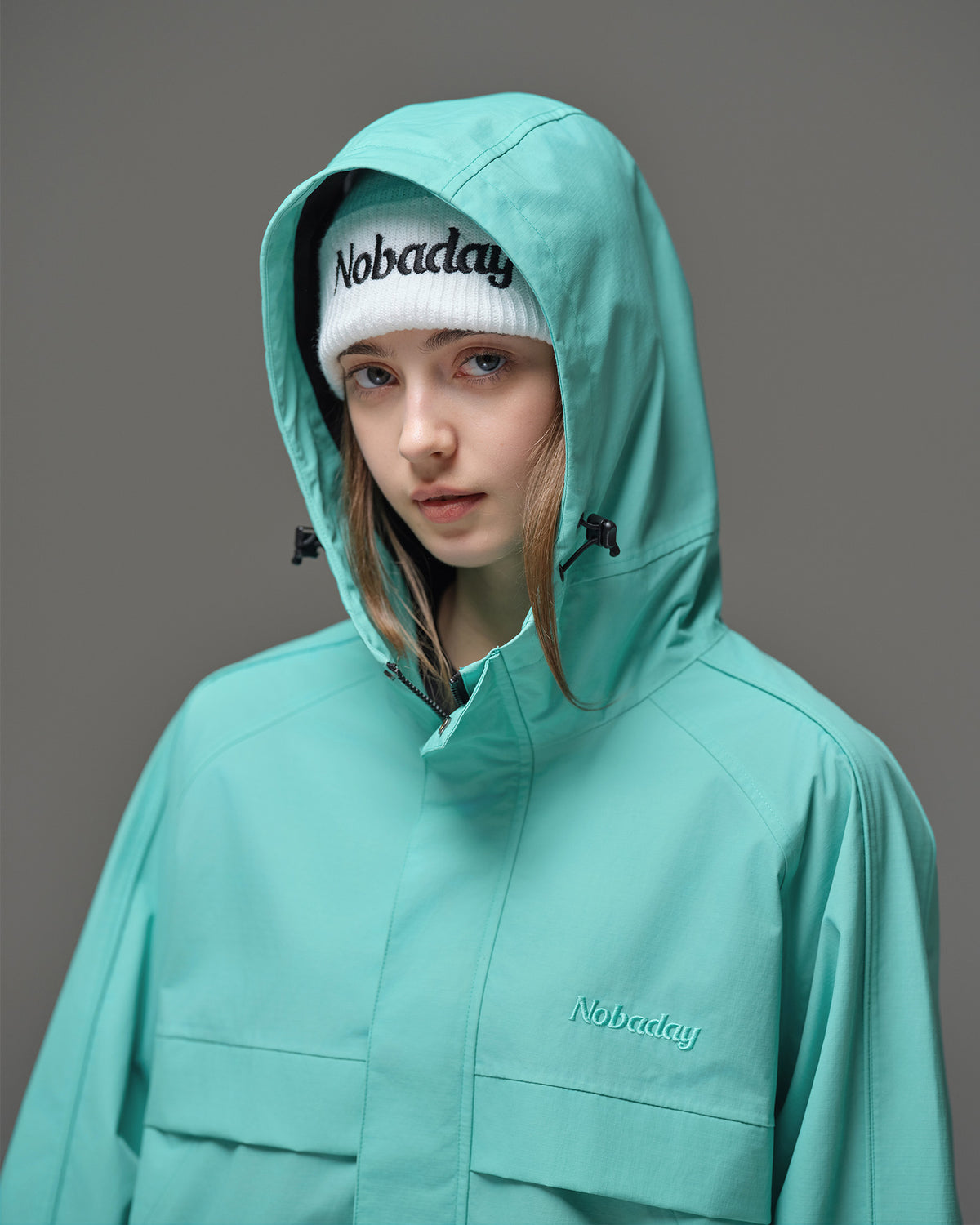 Detail of Nobaday Women's Pure Free Active blue snow jacket with adjustable hood, high collar, storm flap, and embroidered logo