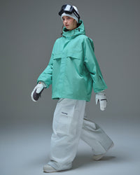 Full body side pose of Nobaday women's blue active snow jacket with white snow pants, mittens, oversized fit, and sleeve pass pocket