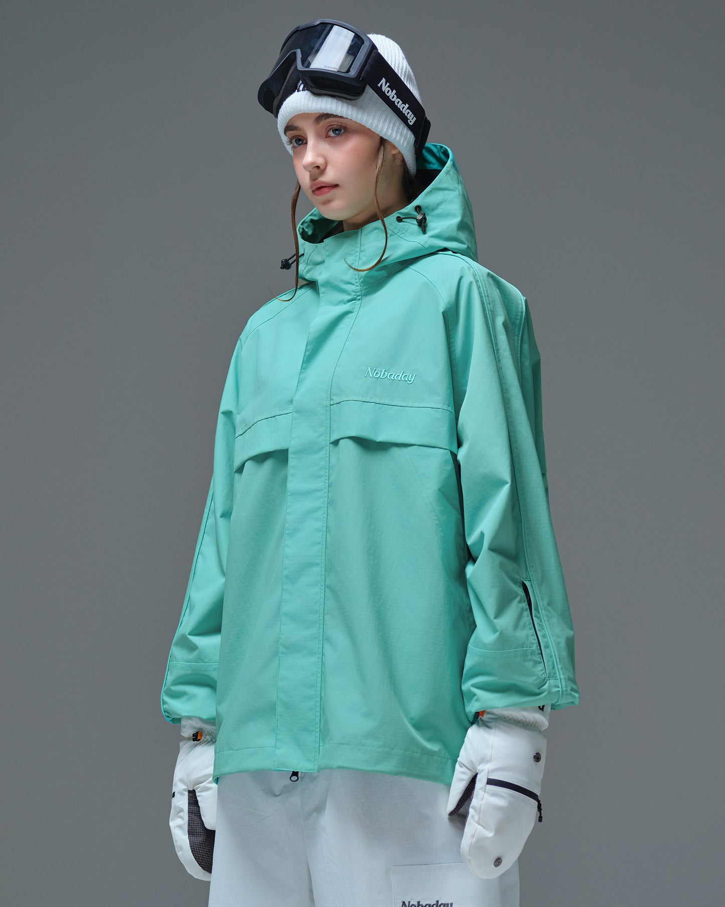 Side view of Nobaday women's blue active snow jacket with adjustable hood, high collar, sleeve pass pocket, and relaxed snowboard fit