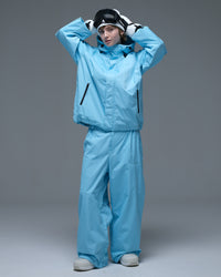 Full-body action pose of a woman wearing the NOBADAY Women's Dawn OG Insulated ice blue snow jacket with matching snow pants