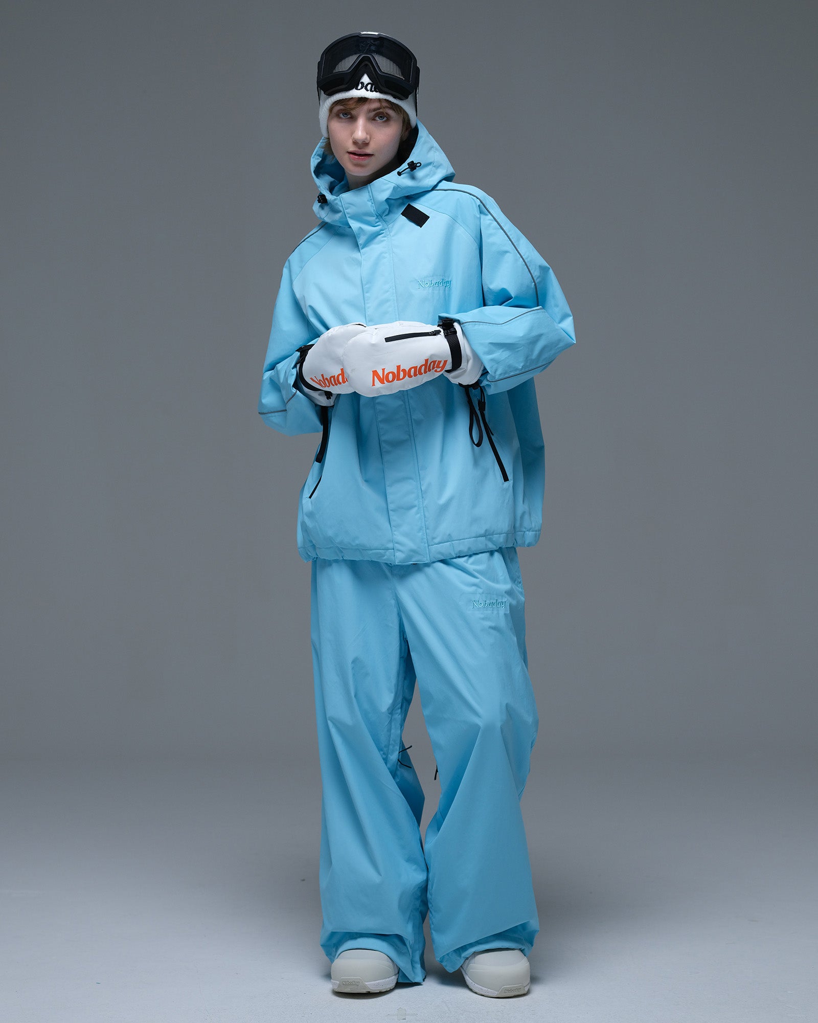 Full-body front view of the NOBADAY Women's Dawn OG Insulated ice blue snow jacket with matching pants and white mittens