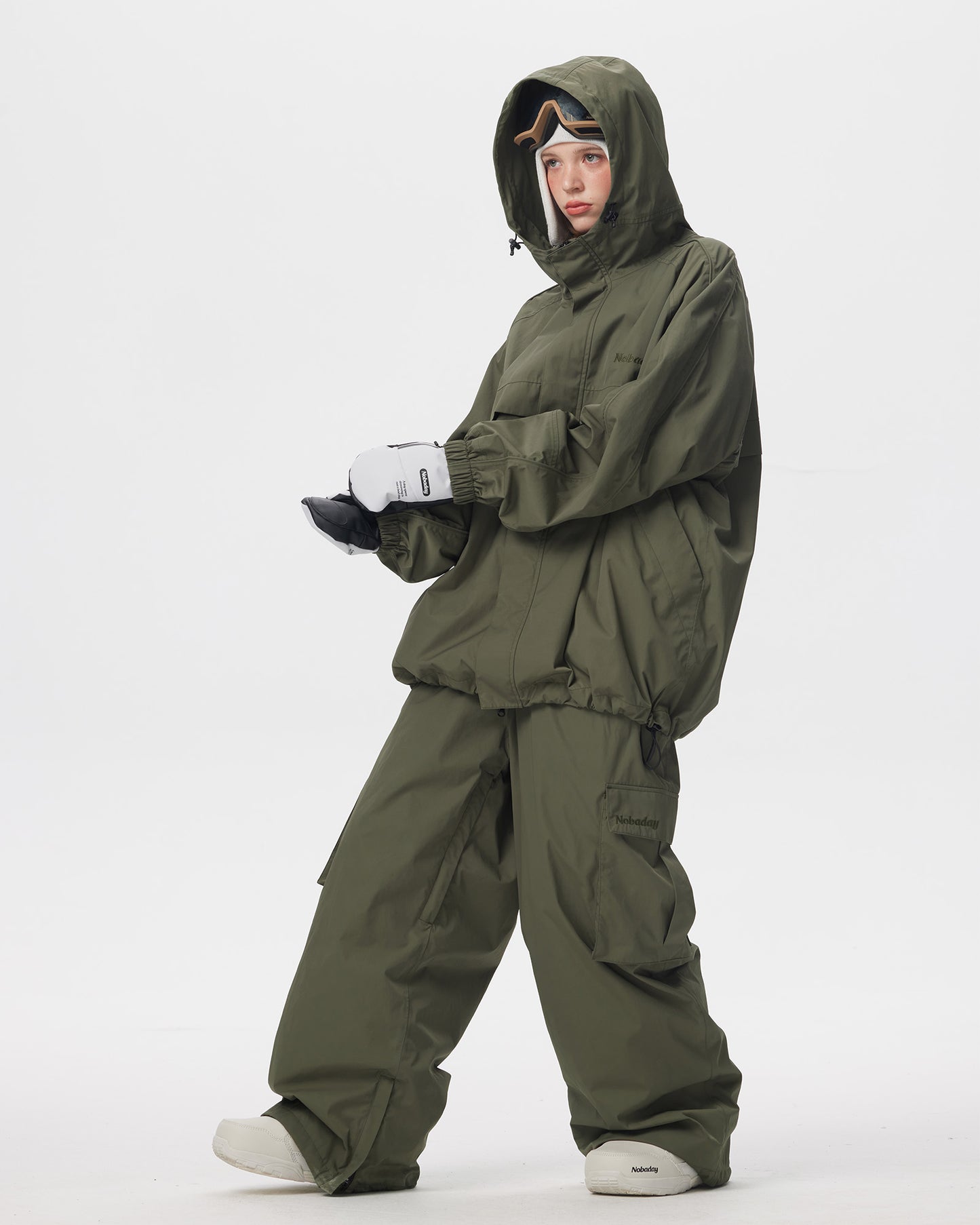 Full body side pose of Nobaday women's green snow jacket with drawcord hem, roomy sleeves, and matching green snow pants