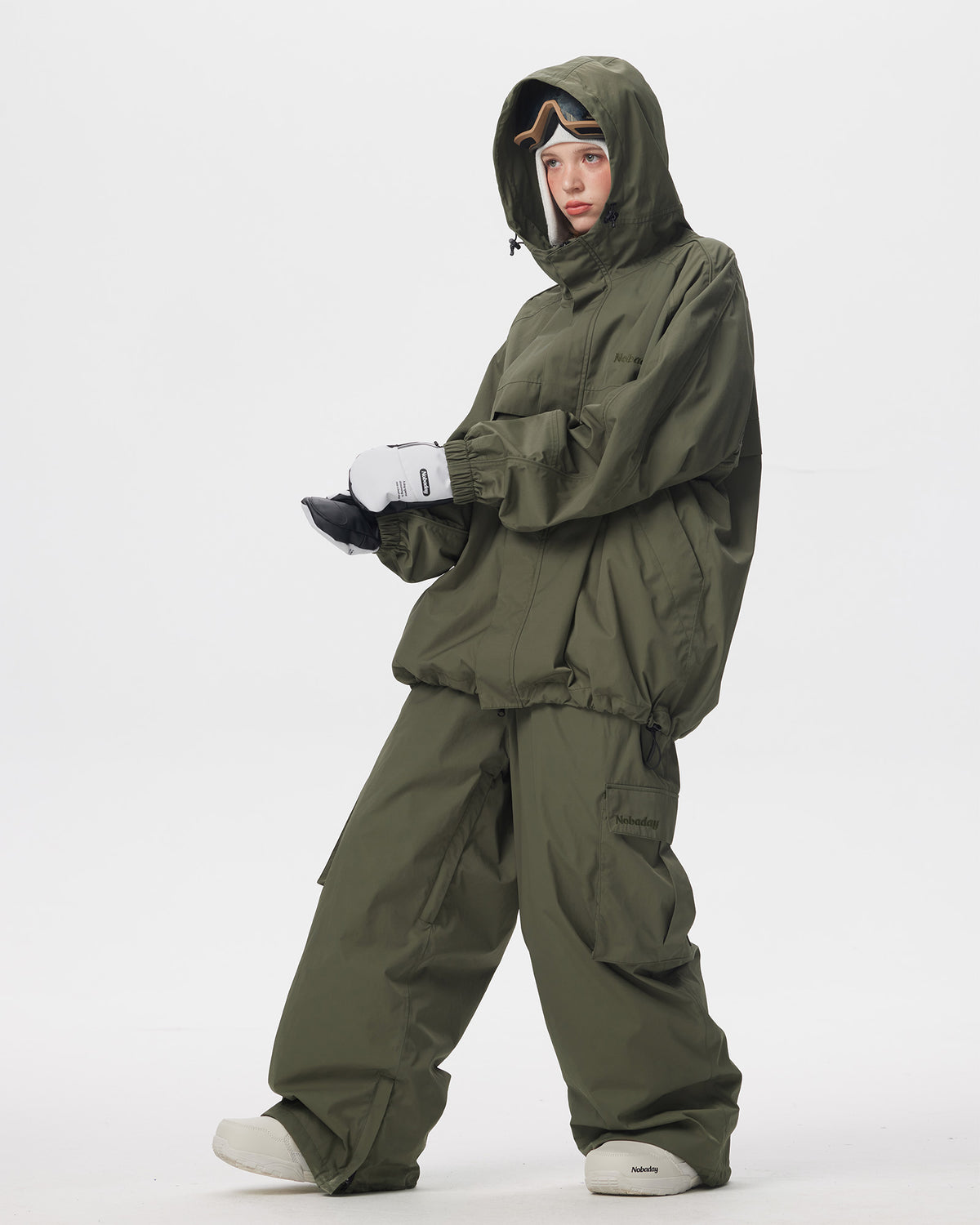 Full body side pose of Nobaday women's green snow jacket with drawcord hem, roomy sleeves, and matching green snow pants