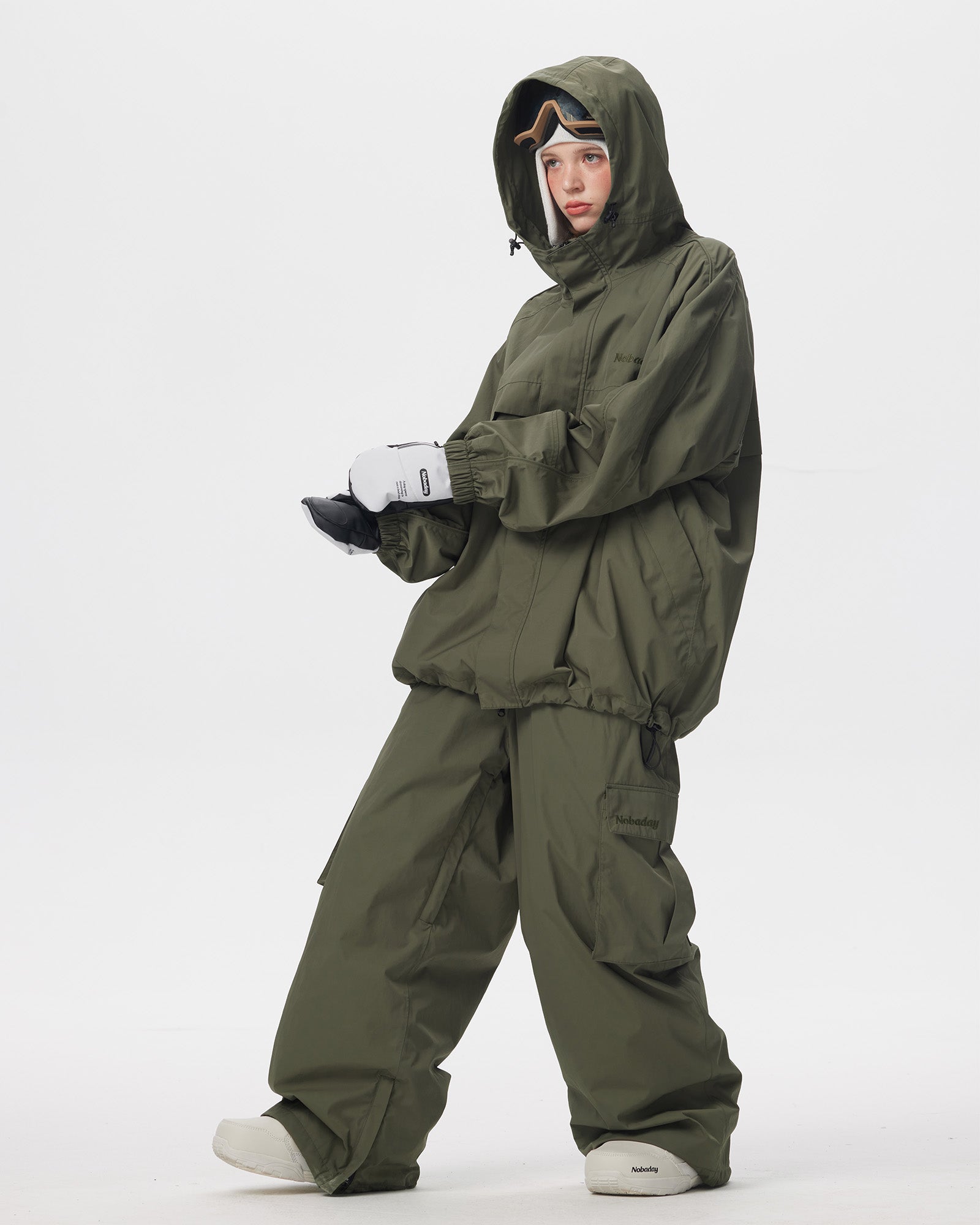 Full body side pose of Nobaday women's green snow jacket with drawcord hem, roomy sleeves, and matching green snow pants