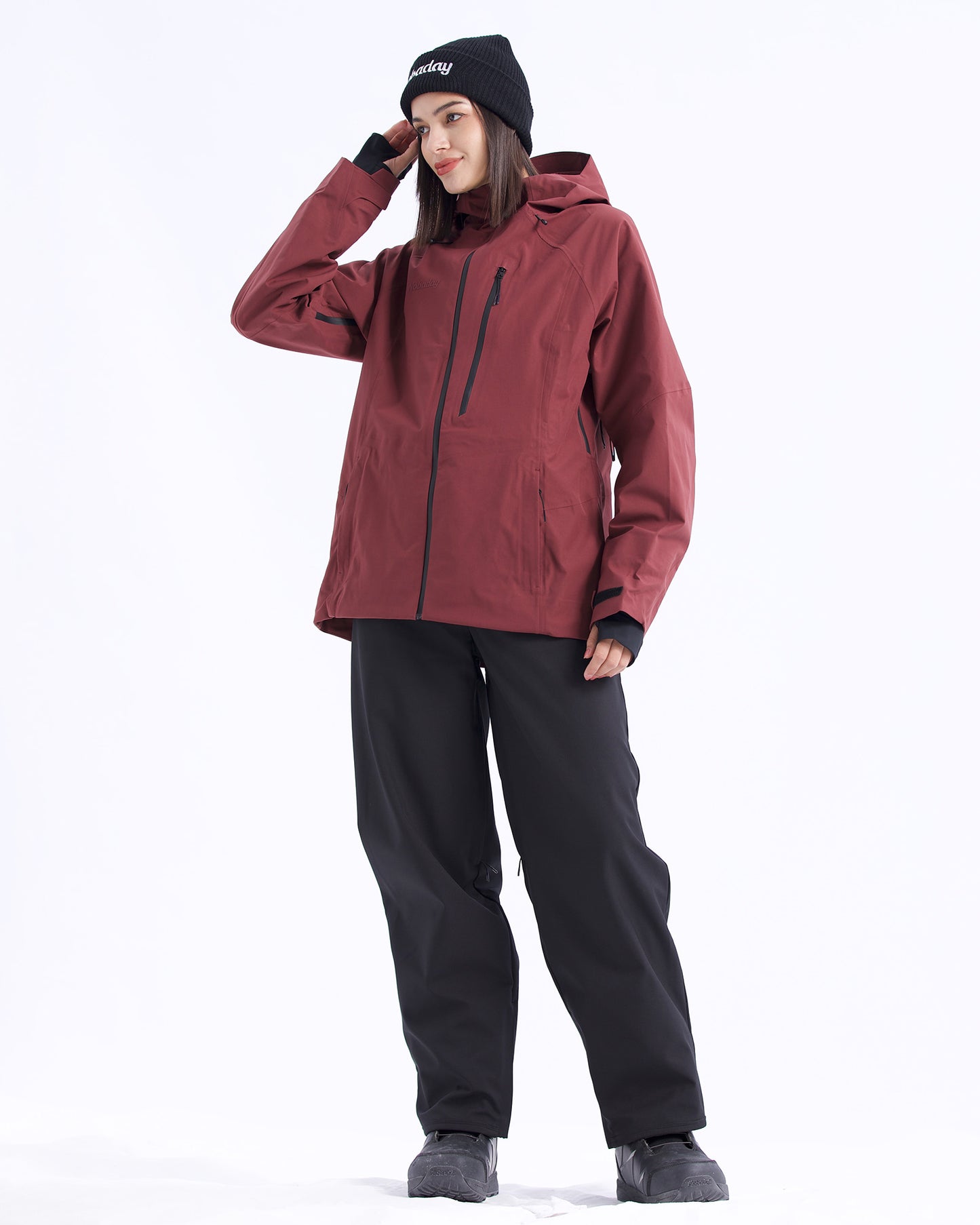 Full-body pose of a woman wearing the NOBADAY Women's Juicy 3L dark red snow jacket with black snow pants