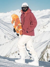 Female snowboarder wearing the NOBADAY Women's Juicy 3L dark red waterproof snow jacket while carrying a snowboard on a snowy mountain