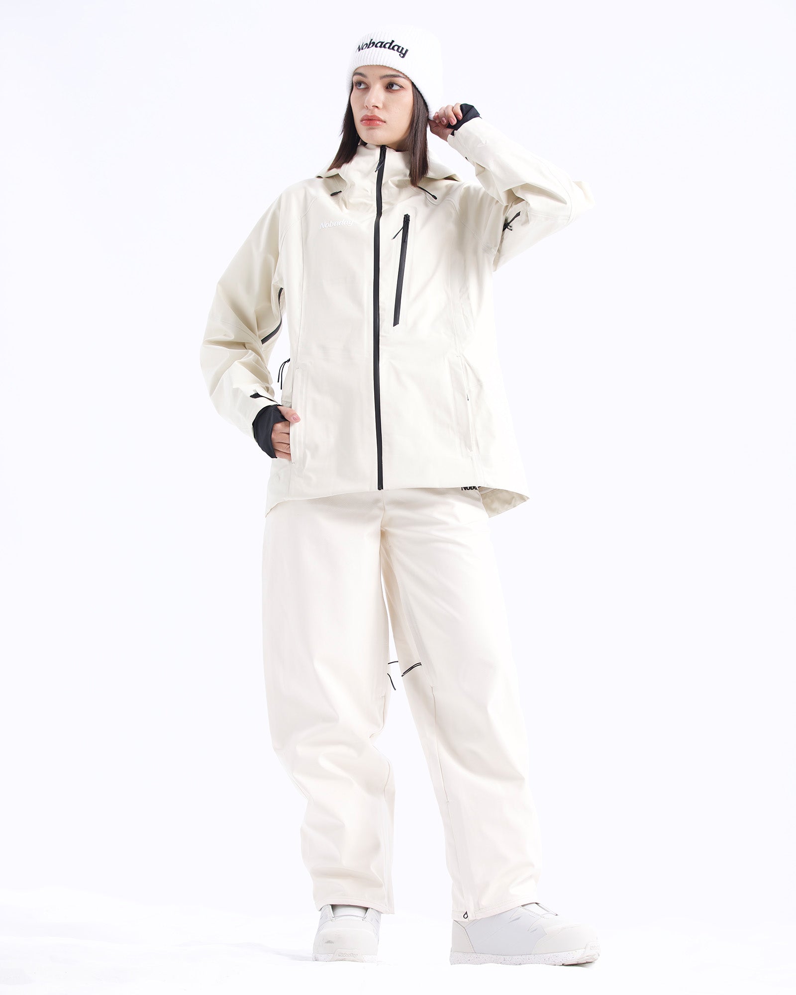 Full-body pose of a woman wearing the NOBADAY Women's Juicy 3L white snow jacket with matching white snow pants