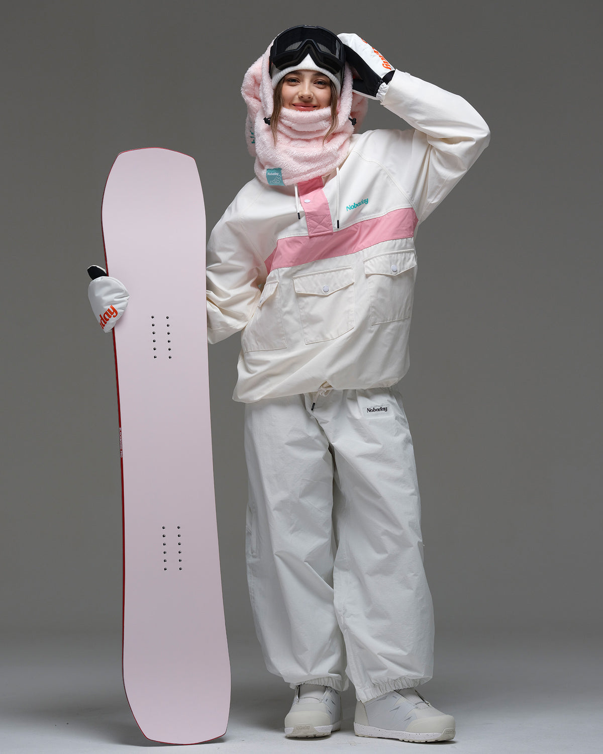 Model wearing the ivory and pink Nobaday Women’s Juicy Candy Retro Snow Jacket while holding a pink snowboard.