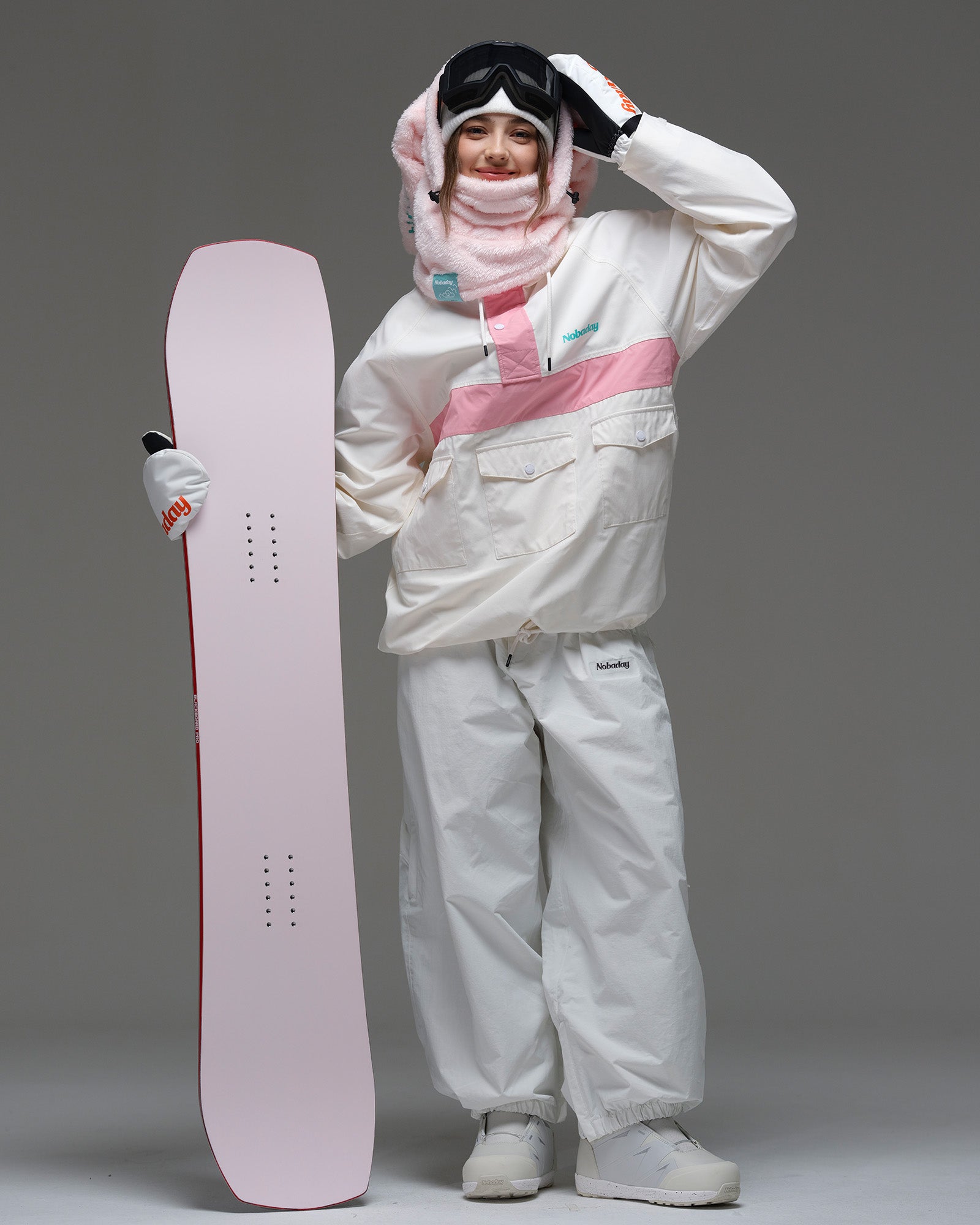 Model wearing the ivory and pink Nobaday Women’s Juicy Candy Retro Snow Jacket while holding a pink snowboard.