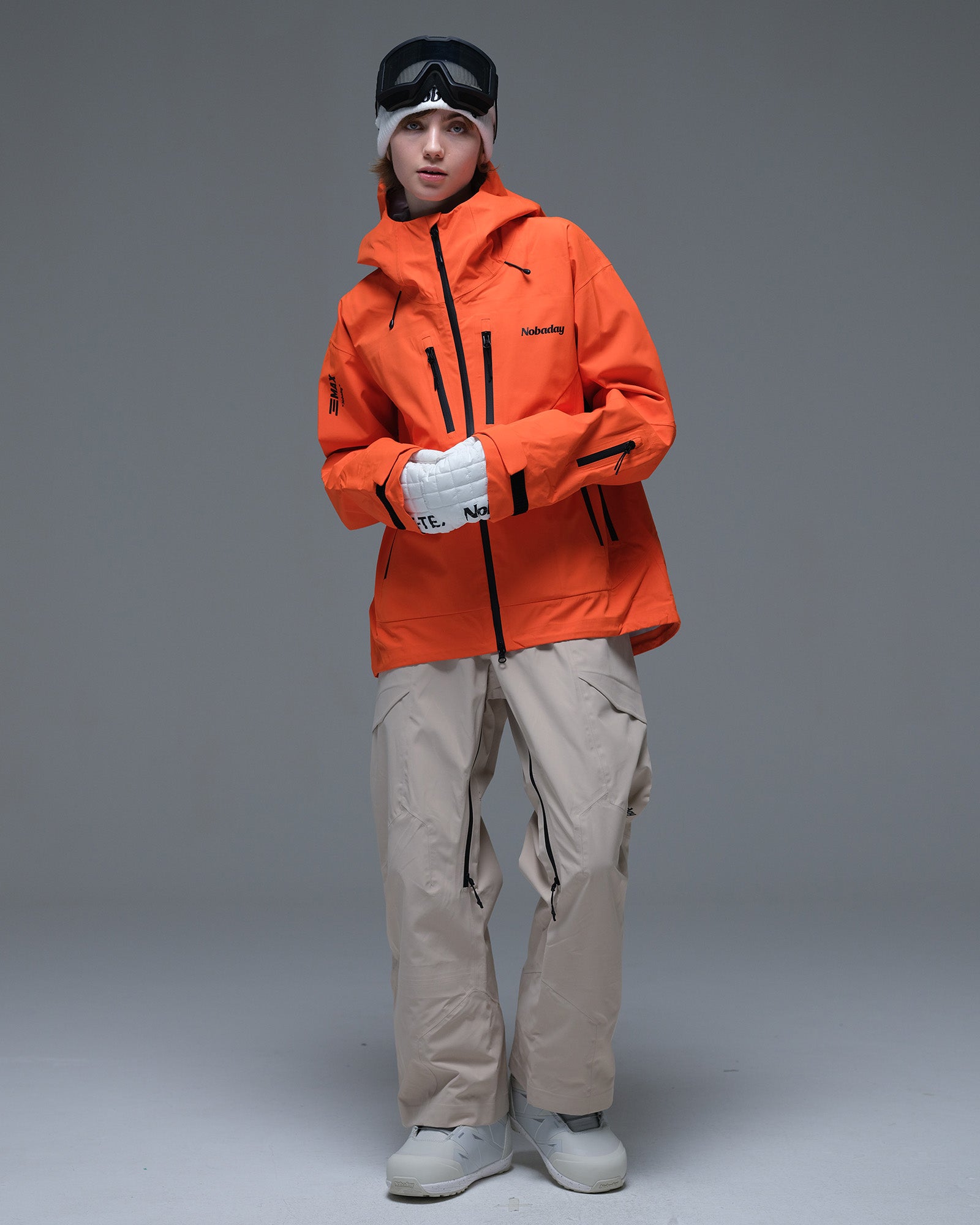 Full-body view of the orange Nobaday Women’s MaxExtreme Pro Zip-Up 3L Snow Jacket featuring multiple zippered pockets and an adjustable hood