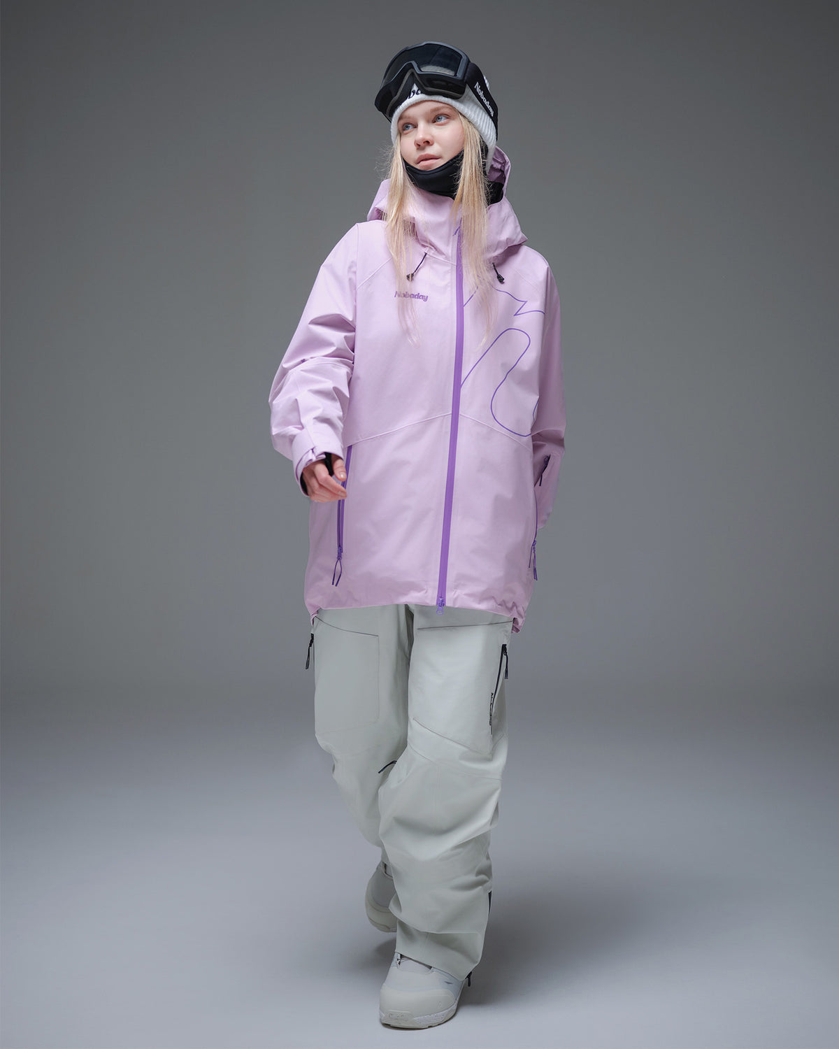 Woman wearing a pink NOBADAY GORE-TEX snow jacket with white snowboard pants