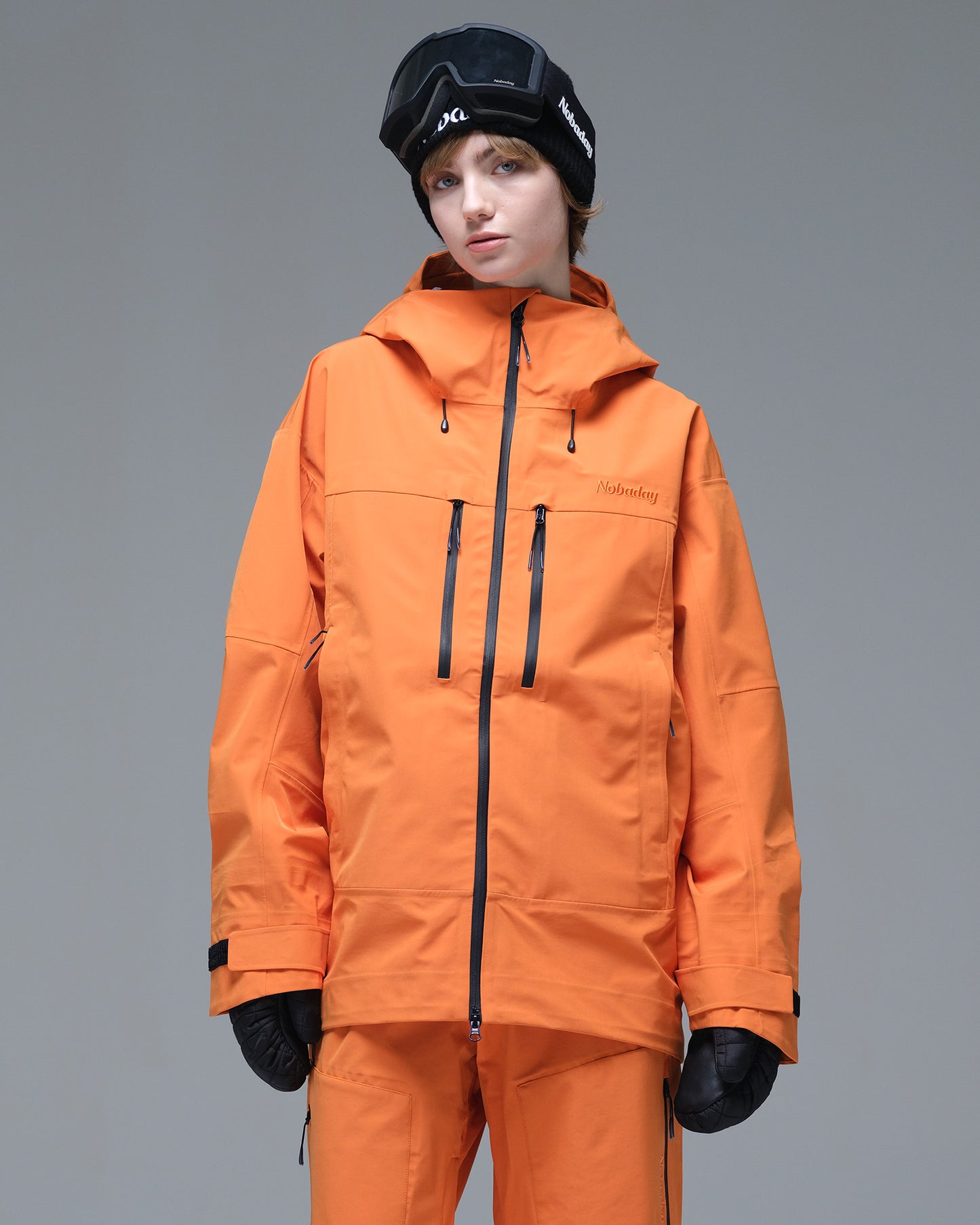Front view of the NOBADAY Women's Pure Free 3L orange waterproof snow jacket with dual chest pockets and adjustable cuffs