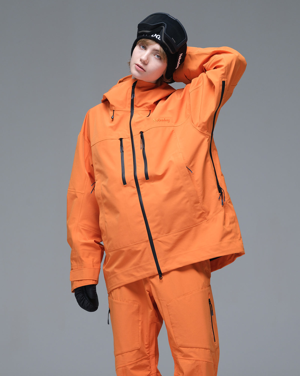 Half-body pose of a woman wearing the NOBADAY Women's Pure Free 3L orange snow jacket with an adjustable hood and chest pockets