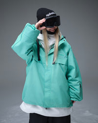 Nobaday Women's Pure Free Active blue snow jacket layered over white midlayer with goggles, oversized sleeves, storm flap, and sleeve pass pocket