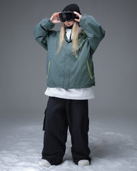 Nobaday Women's Pure Free Active green snow jacket layered over a white midlayer with goggles, oversized sleeves, and snowboard fit