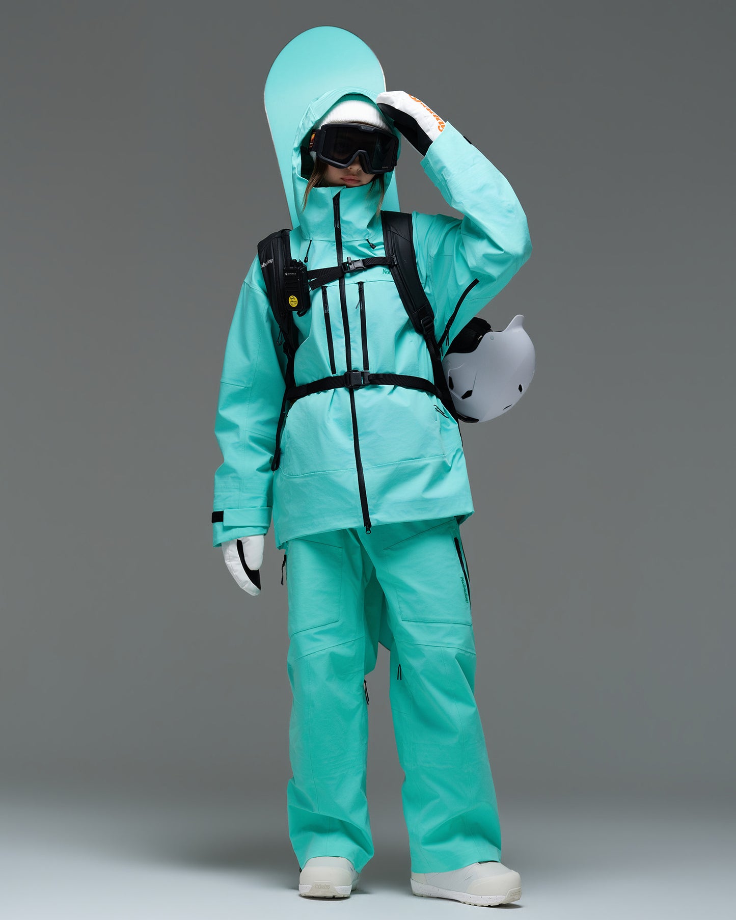 Woman wearing the Nobaday Pure Free Apex 3L waterproof breathable snow jacket in blue with snowboard gear and a helmet