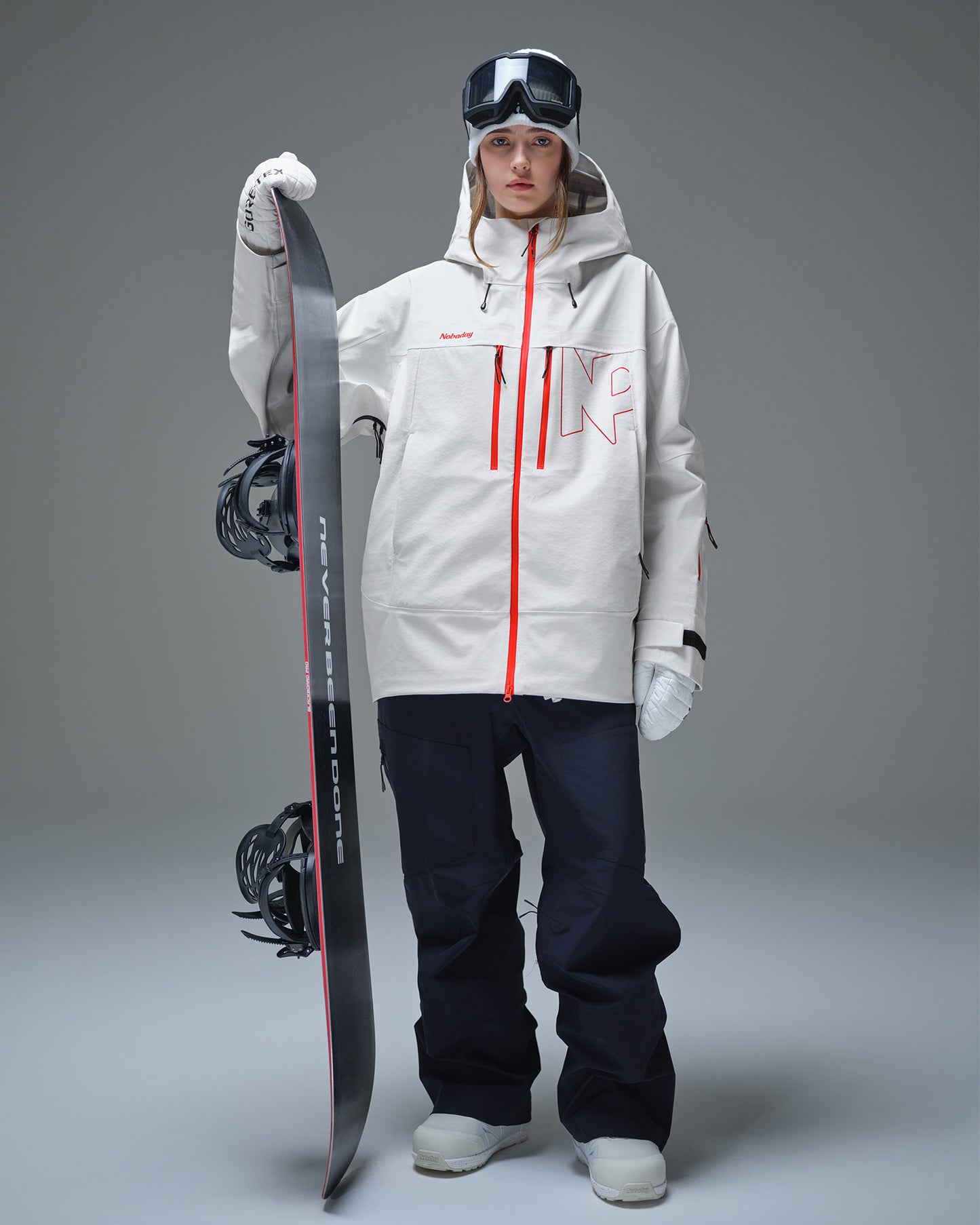 Woman wearing the Nobaday Pure Free Apex 3L waterproof snow jacket in white while holding a snowboard