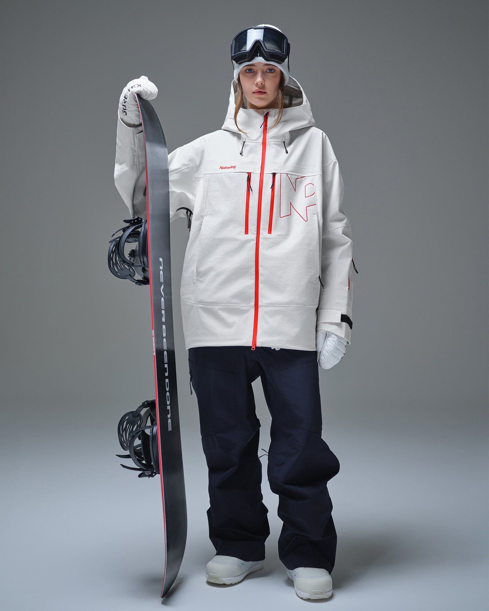 Woman wearing the Nobaday Pure Free Apex 3L waterproof snow jacket in white while holding a snowboard