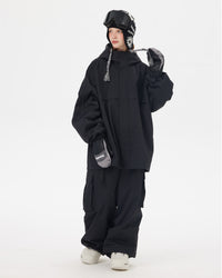 Full body view of Nobaday Women's Pure Free black snow jacket with oversized fit, protective hood, snow goggles, and black snow pants